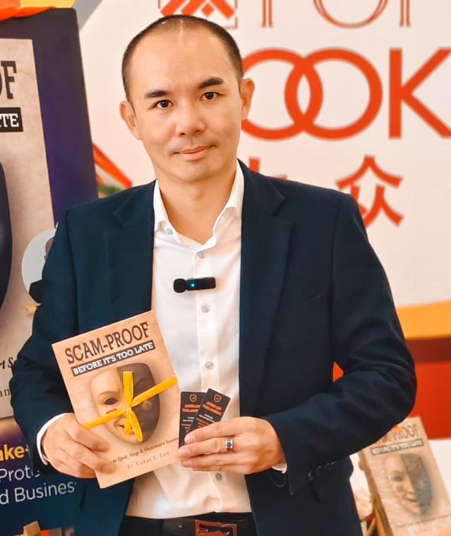 Ts. Lukas J. Tan, founder of K Publisher, holding a copy of Scam-Proof