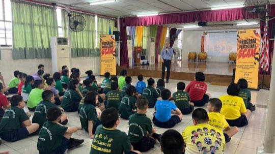 A school hall full of students learning about scams